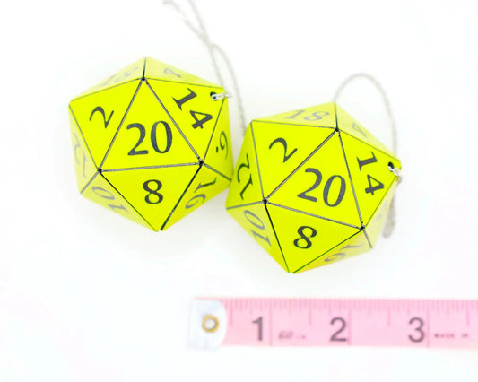 Pair of neon yellow 20-sided dice car charms with black numbers and a pink ruler for scale