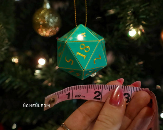 Green twenty-sided dice ornament with gold numbers, measured by tape, on Christmas tree