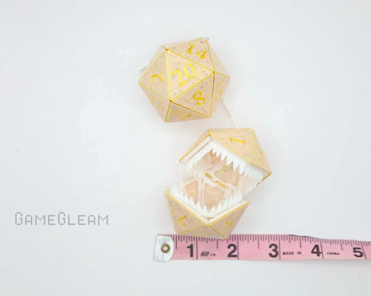 Handmade gold twenty-sided dice charm with teeth, next to measuring tape on white background