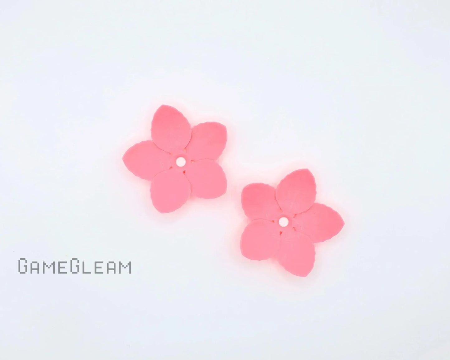 Pair of pink five-petal flower-shaped car charms on white background