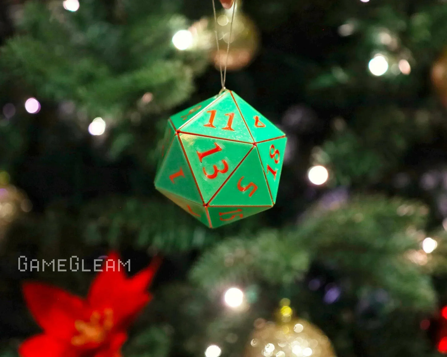 Green twenty-sided dice ornament hanging on a Christmas tree with festive lights.