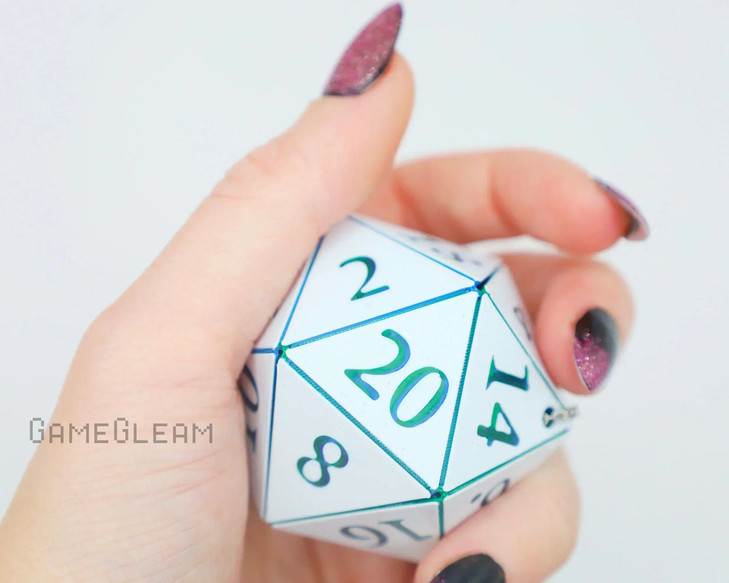 Hand holding large white 20-sided dice with green numbers, close-up, gamer accessory
