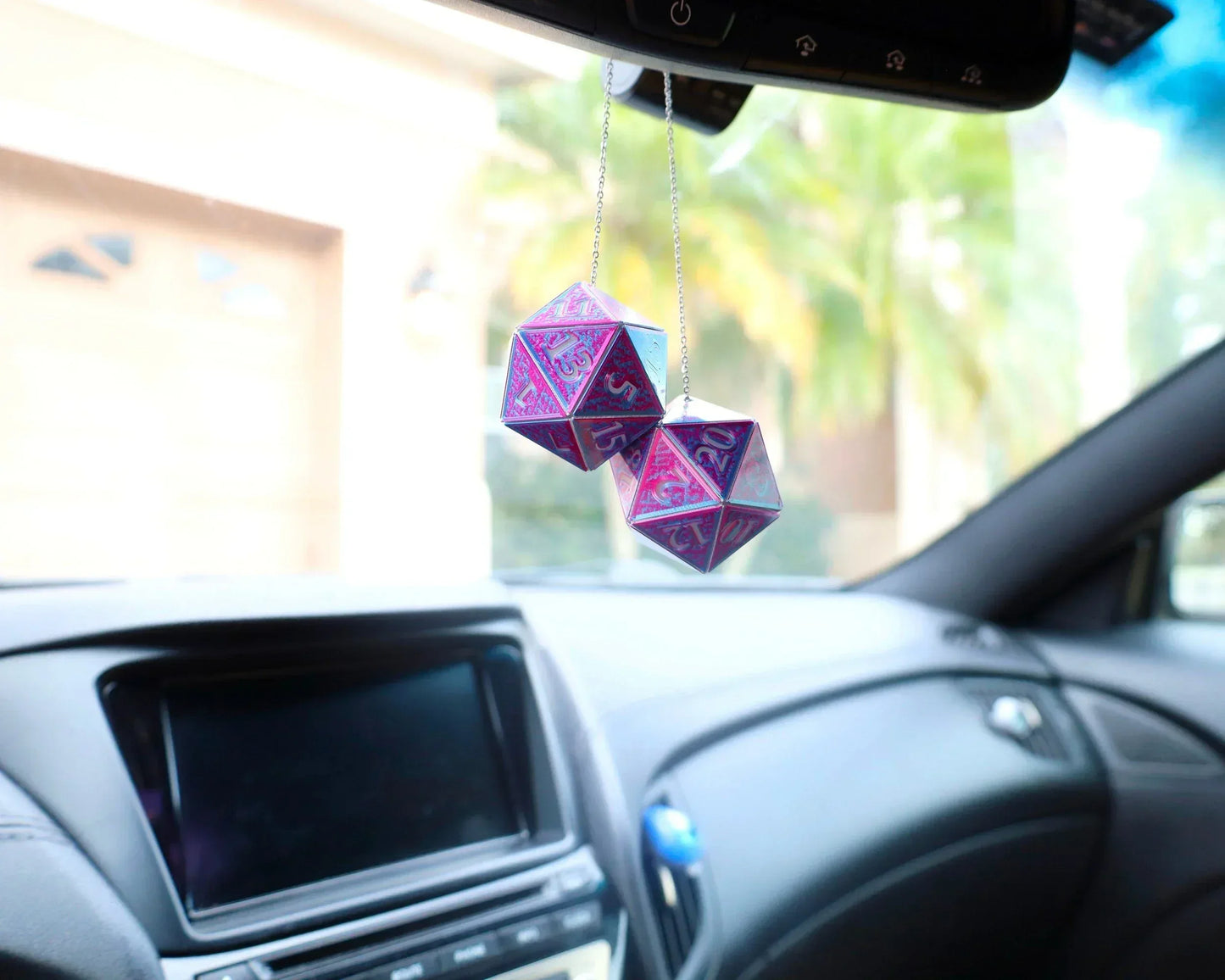 Holographic purple 20-sided dice car charm hanging from rearview mirror in a car interior