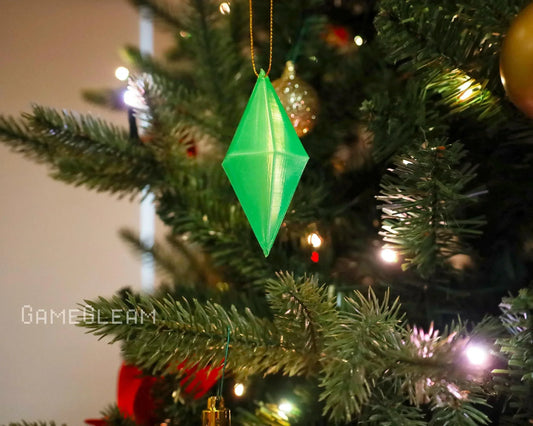 Green geometric crystal ornament hanging on a Christmas tree with festive lights