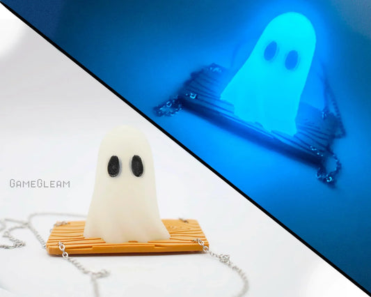 Handmade glow-in-the-dark ghost charm with black eyes on a gold striped base and chain