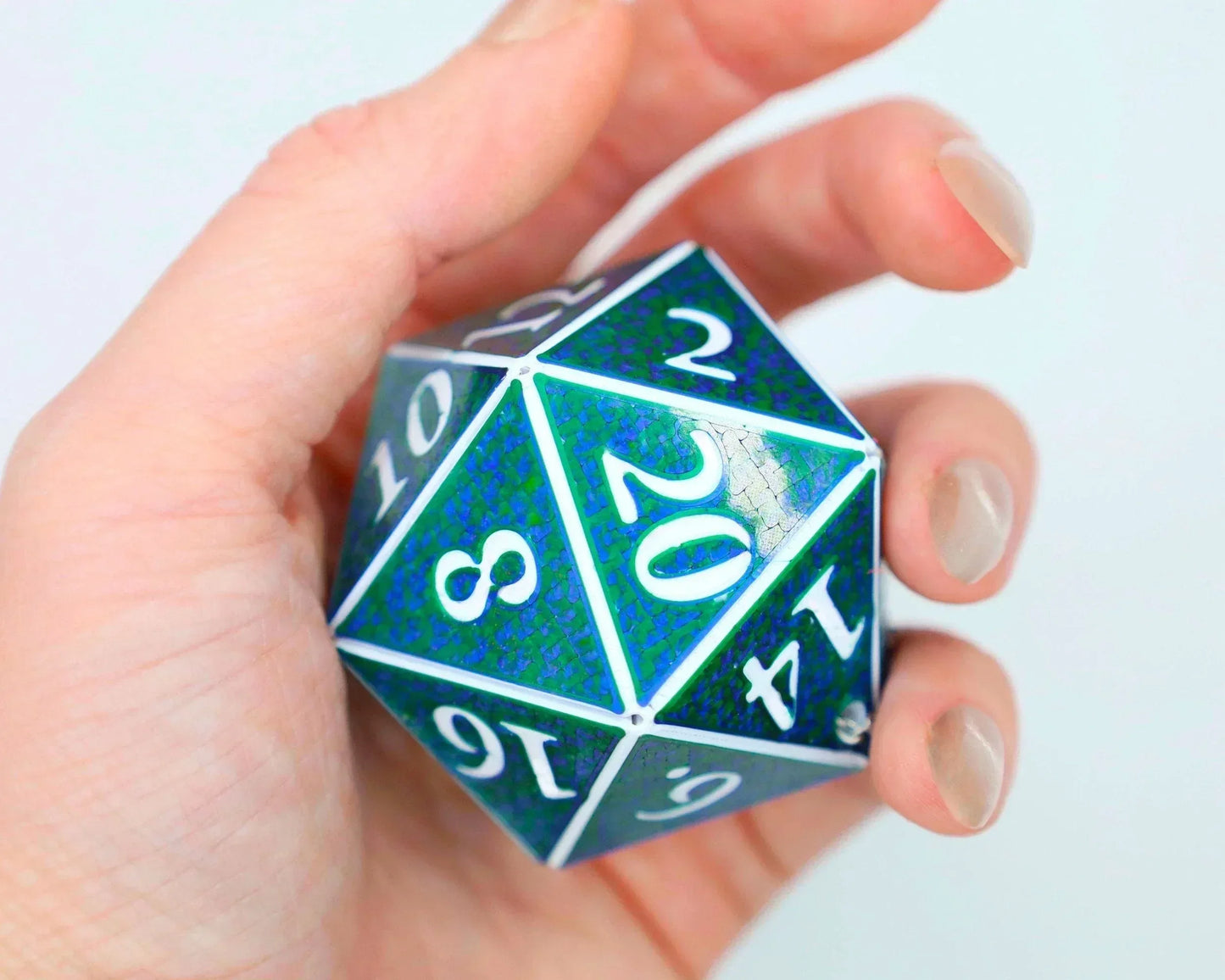 Hand holding large holographic blue and green 20-sided RPG dice with white numbers