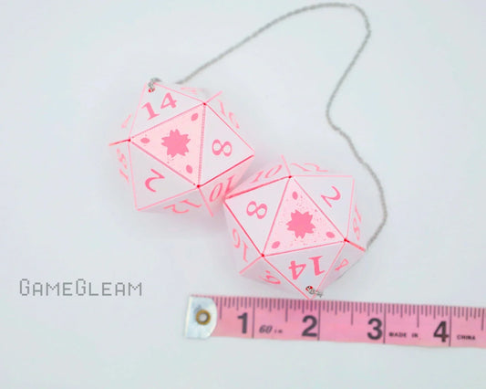 Pair of pink and white twenty-sided car dice charms with measuring tape, perfect for gamer gifts