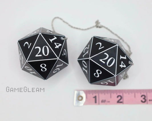 Black and white 20-sided dice car charm set with silver chain, shown next to a pink ruler for scale.