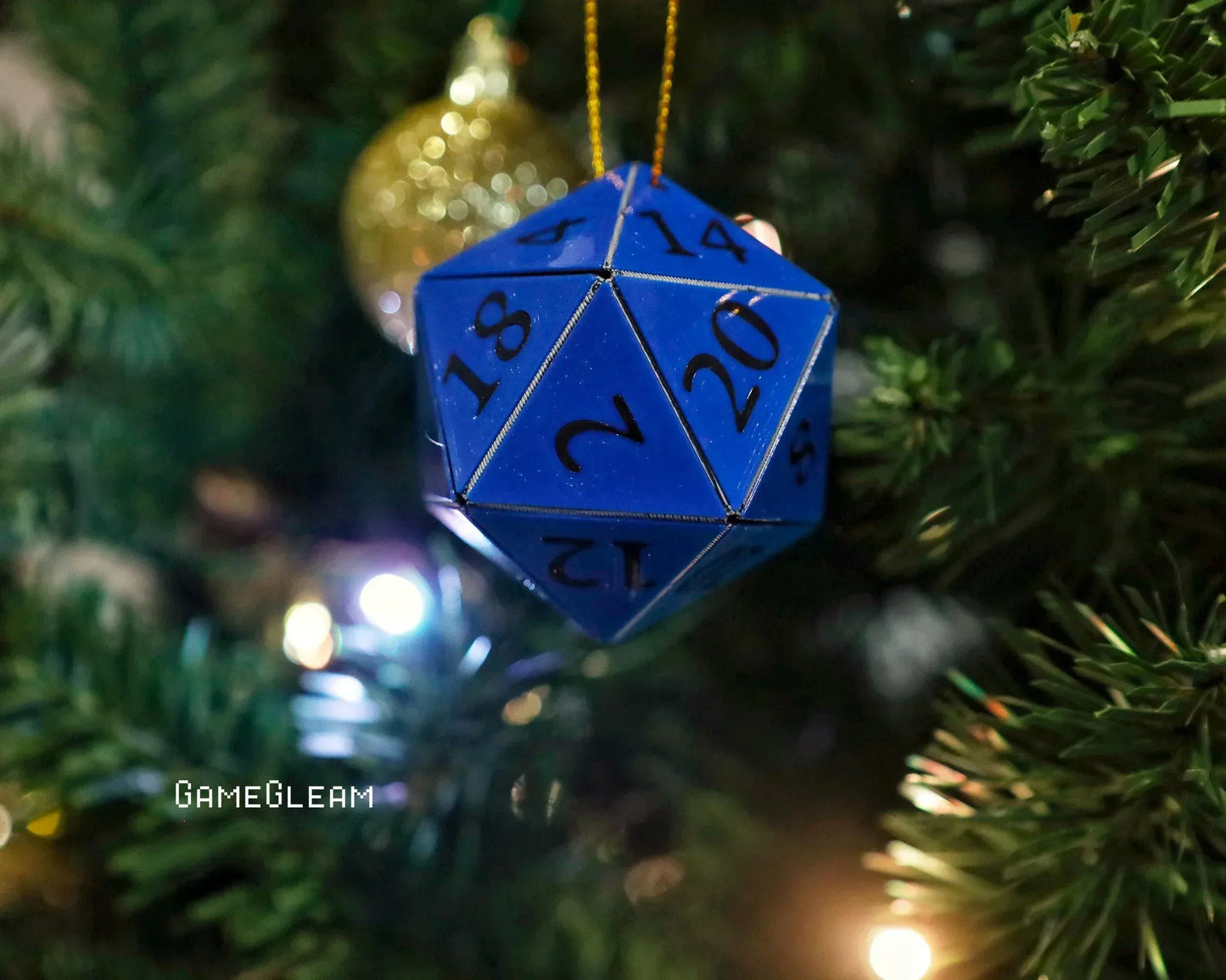 Blue 20-sided dice Christmas ornament hanging on a tree with festive lights