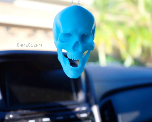 Blue skull-shaped car charm hanging from rearview mirror in vehicle interior