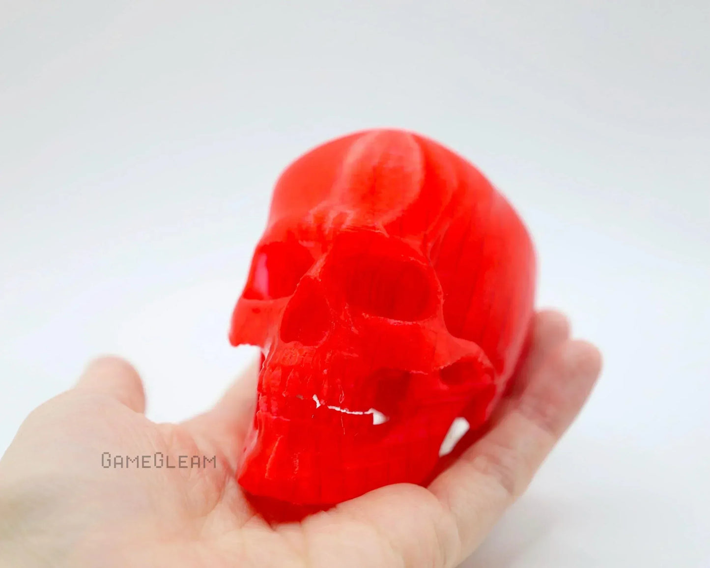Hand holding a bright red resin skull, unique handmade gamer decor accessory