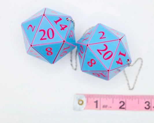 Pair of large blue 20-sided dice with pink numbers, metal chains, and a pink tape measure