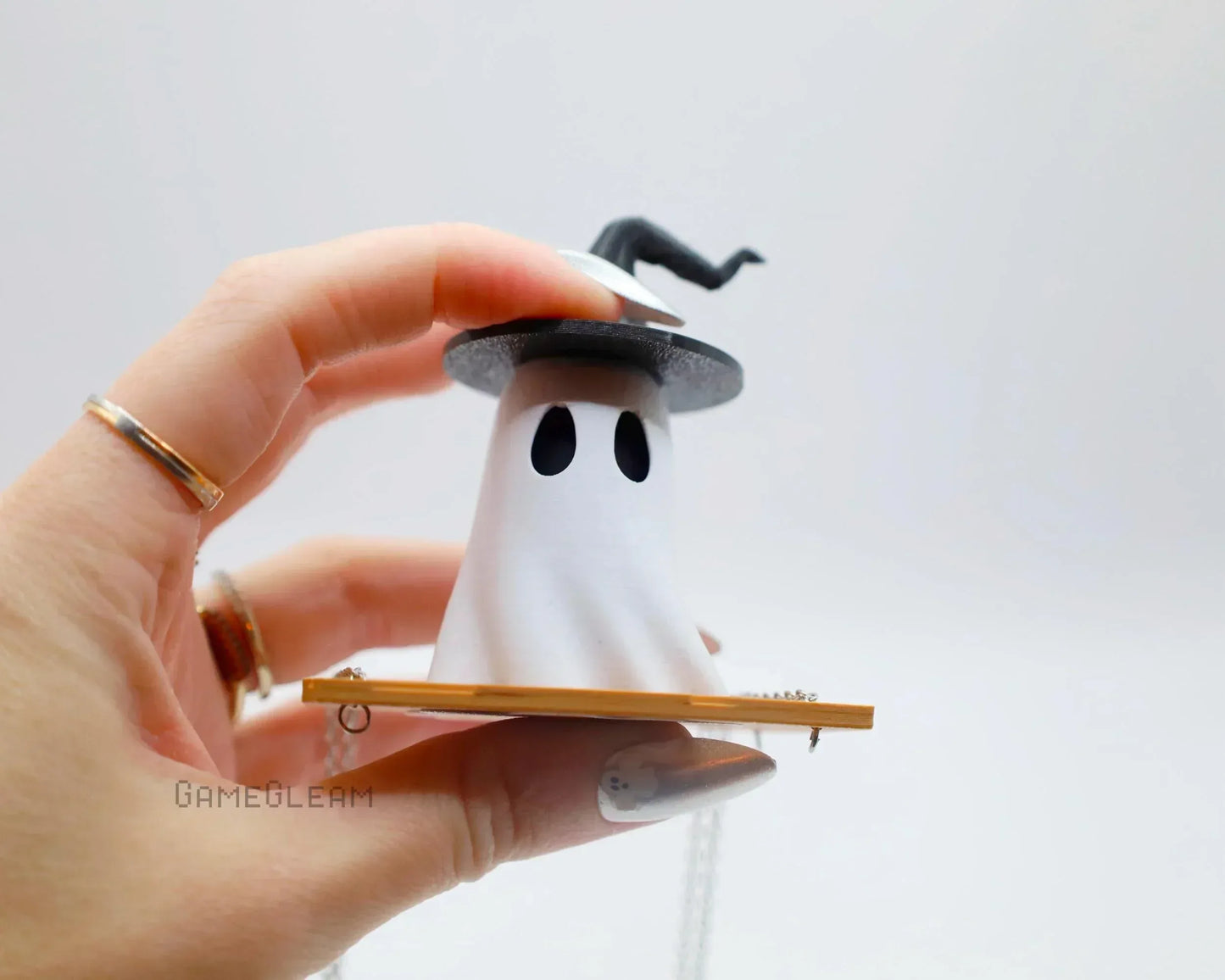 Hand holding a cute ghost car charm with a wizard hat and book, handmade gamer accessory