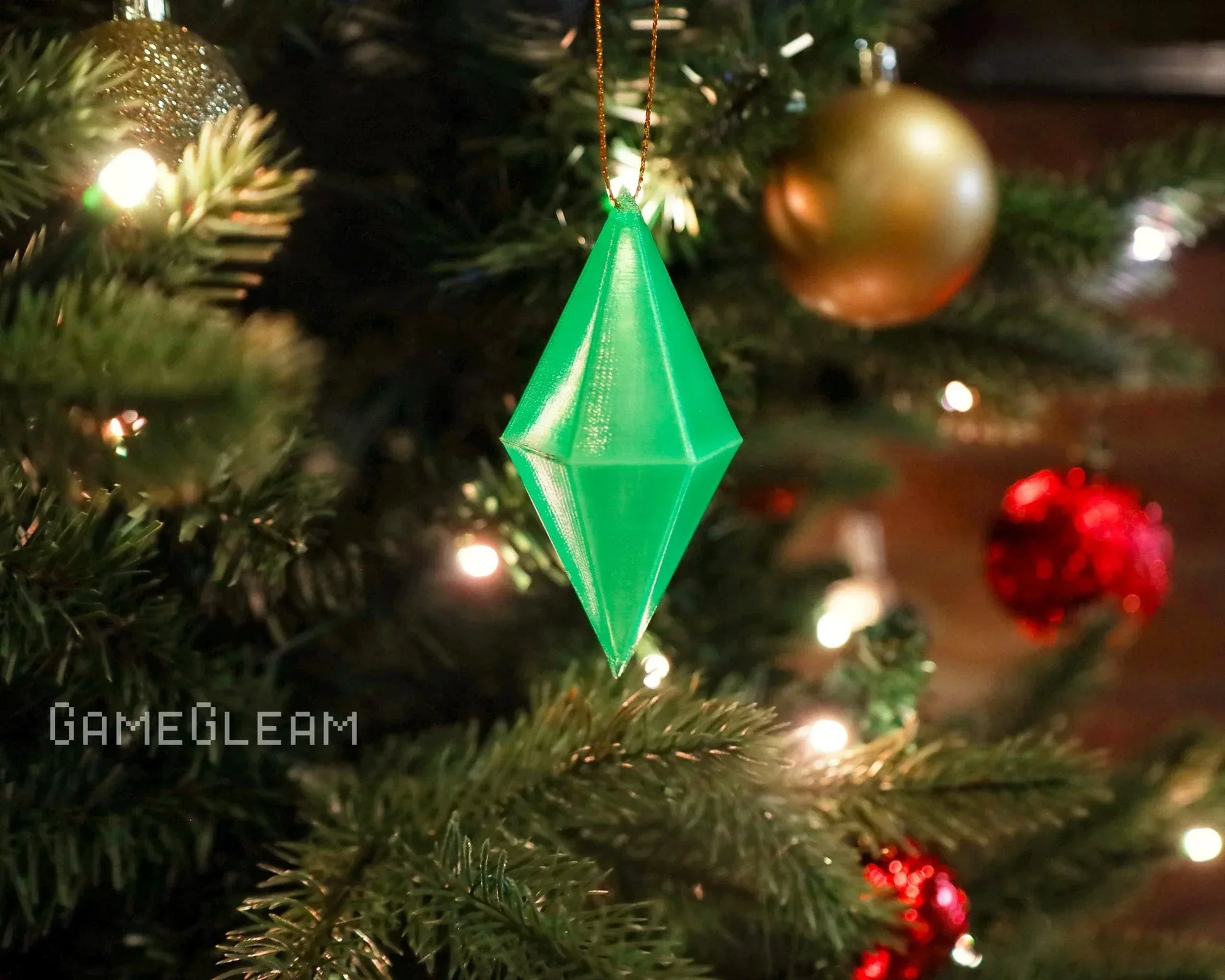 Green geometric crystal ornament hanging on a Christmas tree with festive lights and baubles
