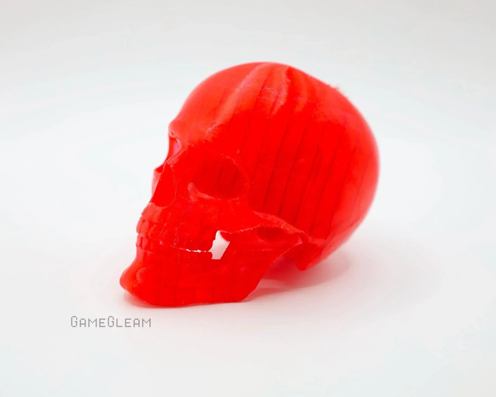 Red translucent skull-shaped resin figurine on a white background