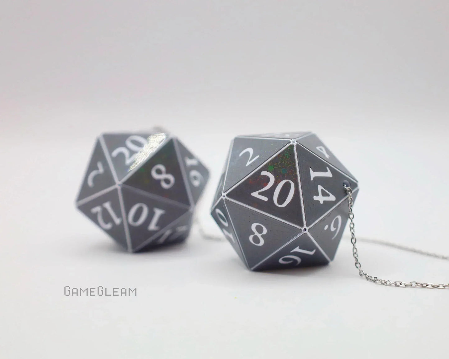 Holographic twenty-sided dice car charms with silver chains on a white background
