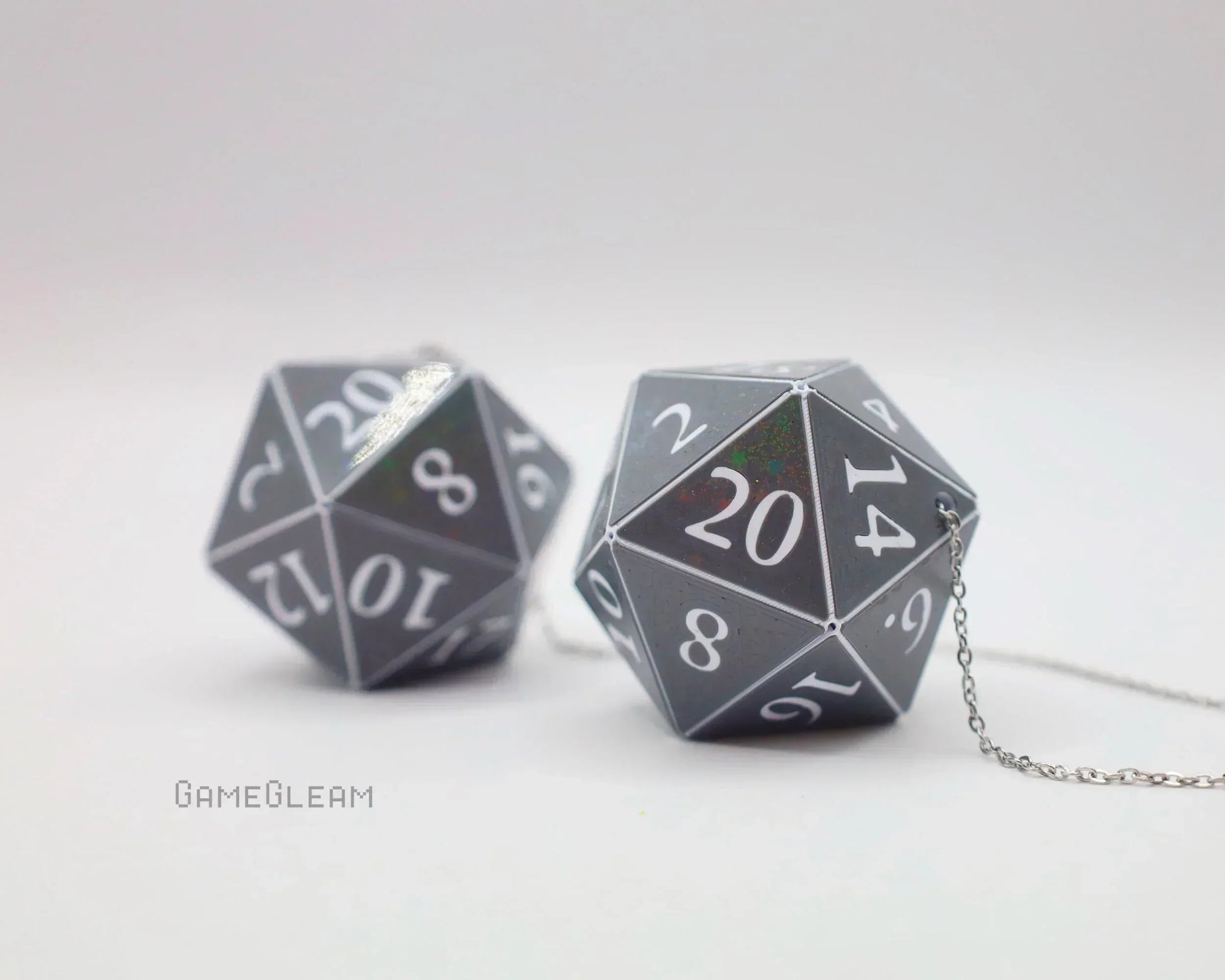 Holographic twenty-sided dice car charms with silver chains on a white background