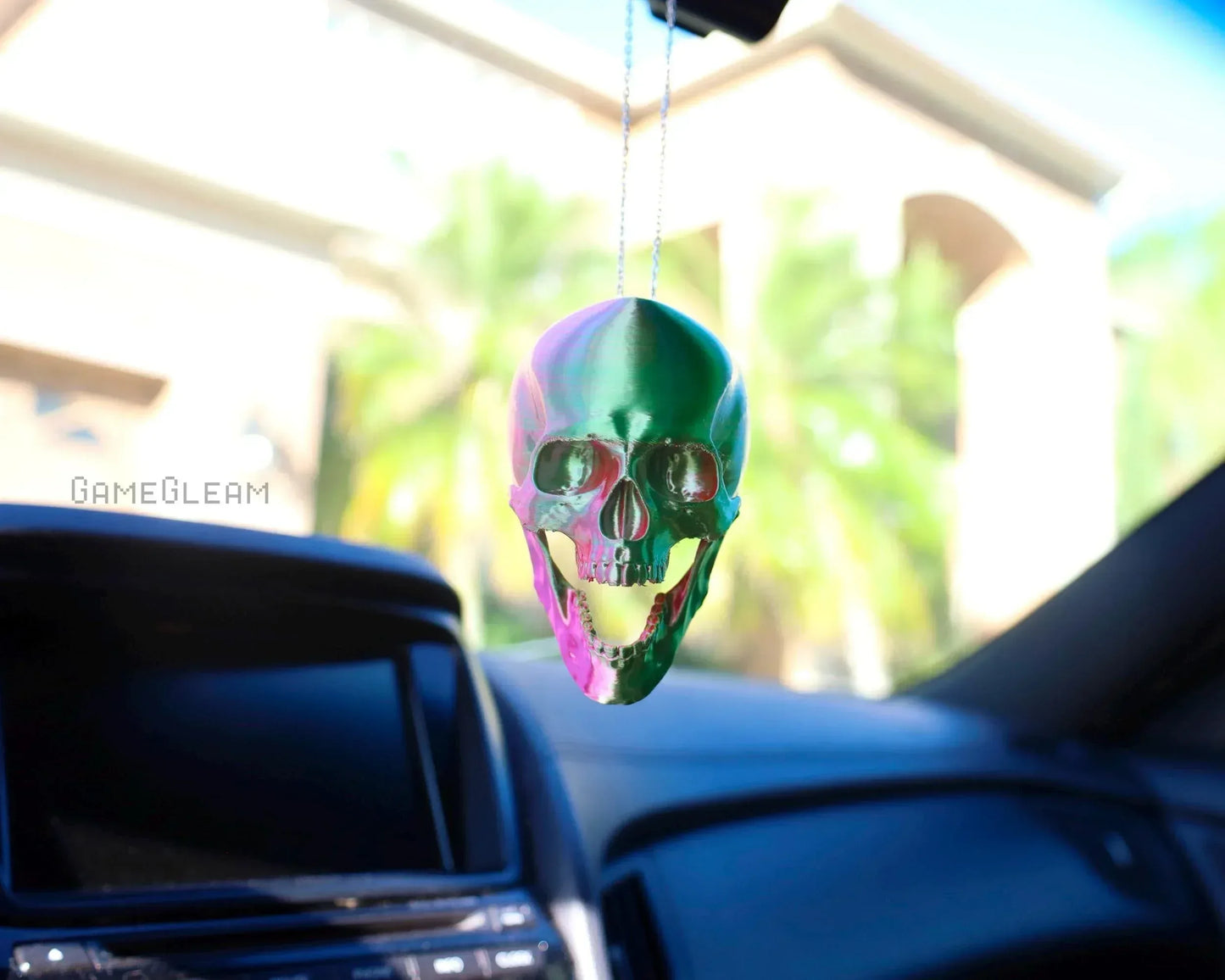 Holographic skull car charm hanging from rearview mirror in a vehicle interior