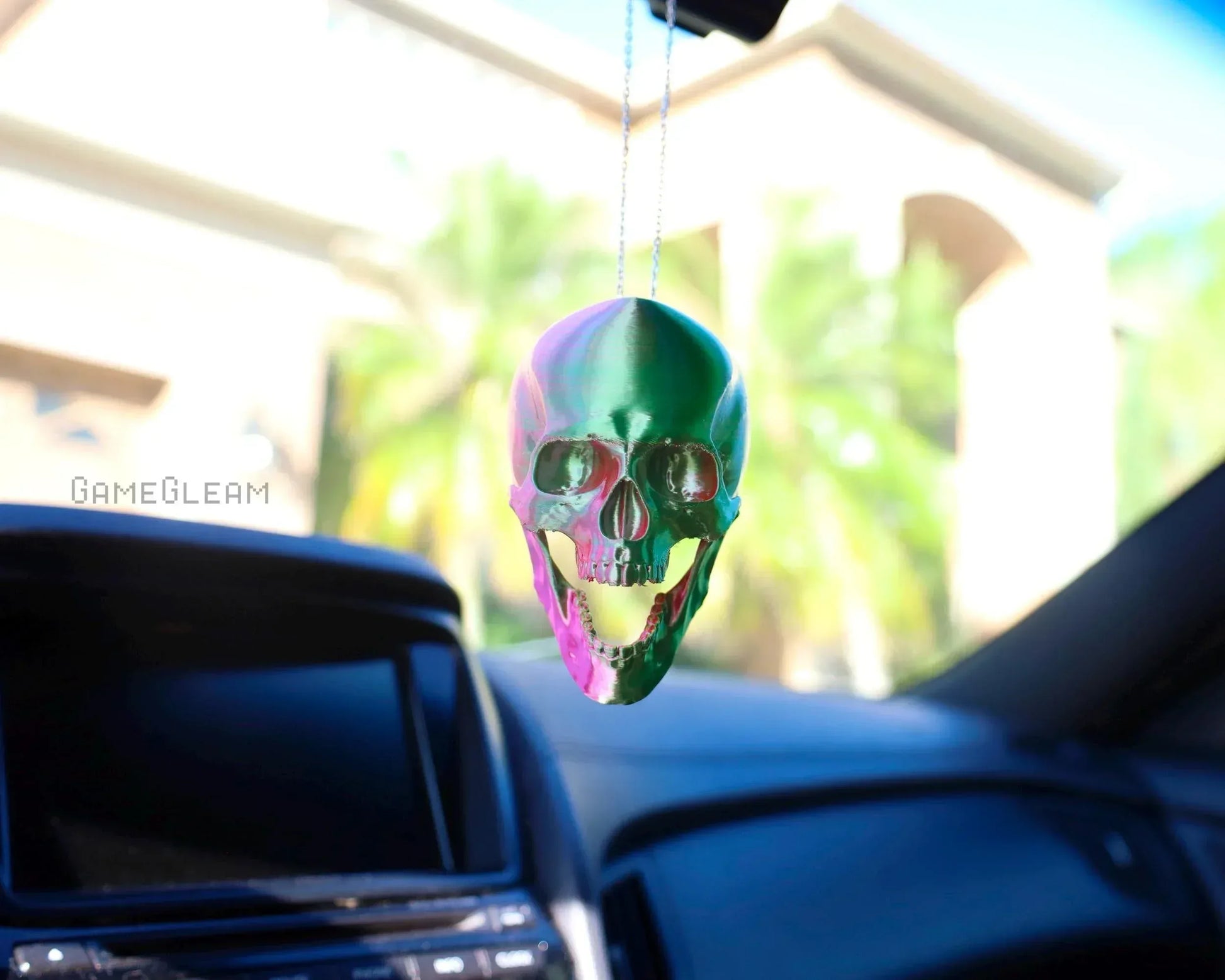 Holographic skull car charm hanging from rearview mirror in a vehicle interior