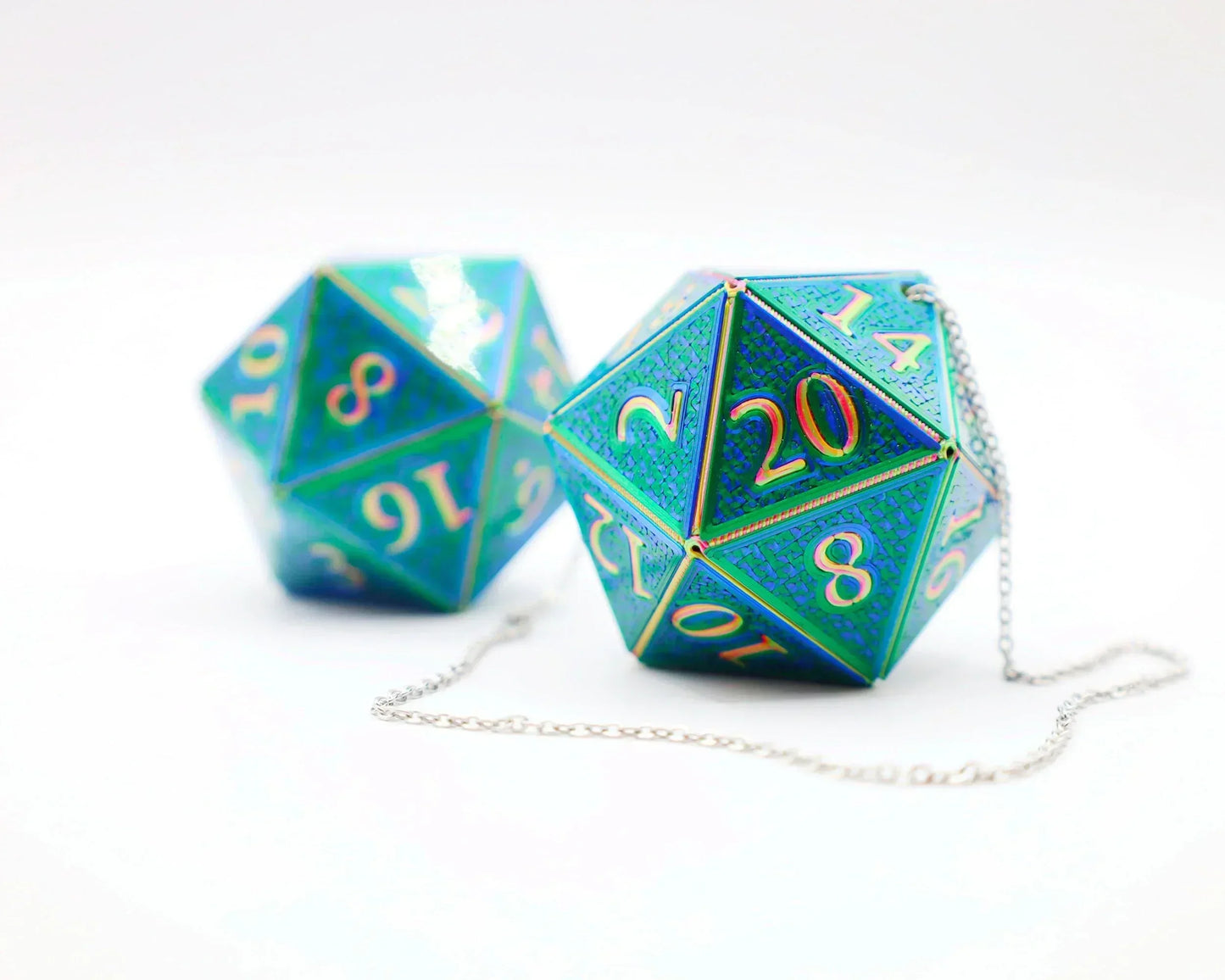 Holographic blue twenty-sided dice with gold numbers and attached silver chain on white background.