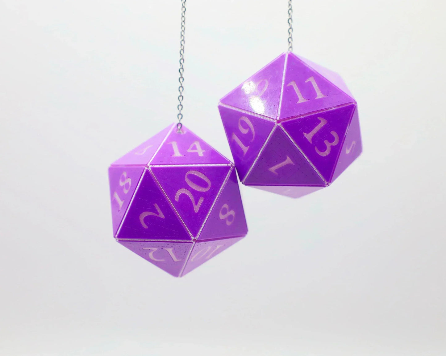 Purple twenty-sided dice car charm with white numbers, hanging on chains against white background.
