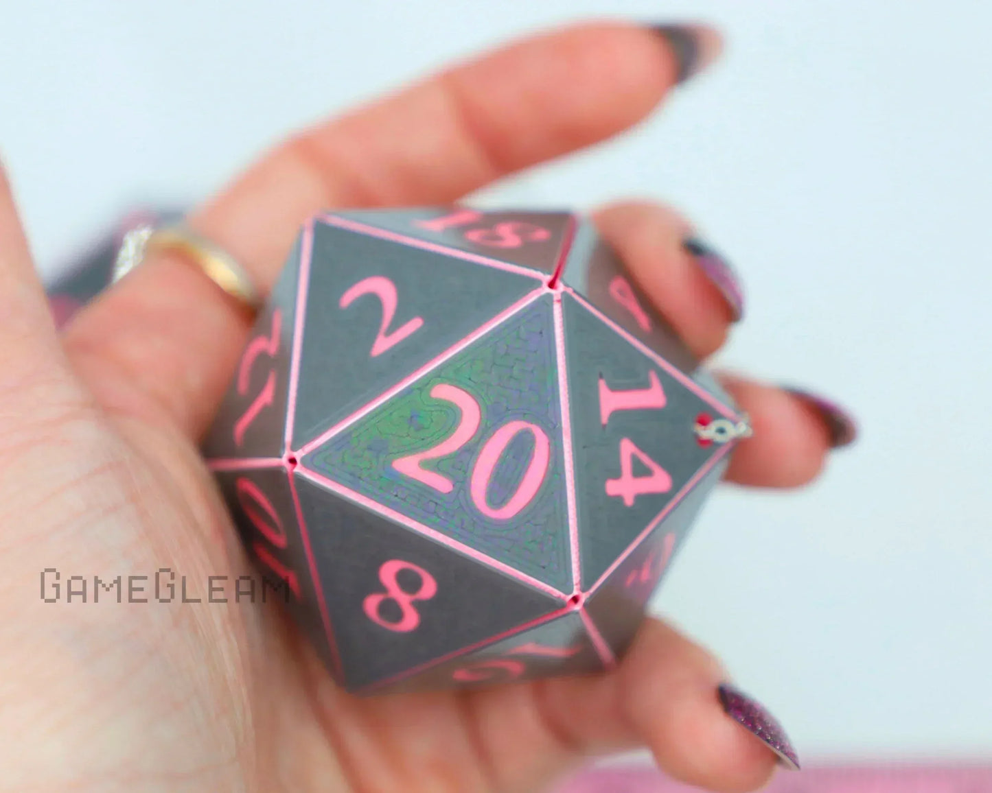 Hand holding large holographic twenty-sided dice with pink numbers, gamer gift accessory