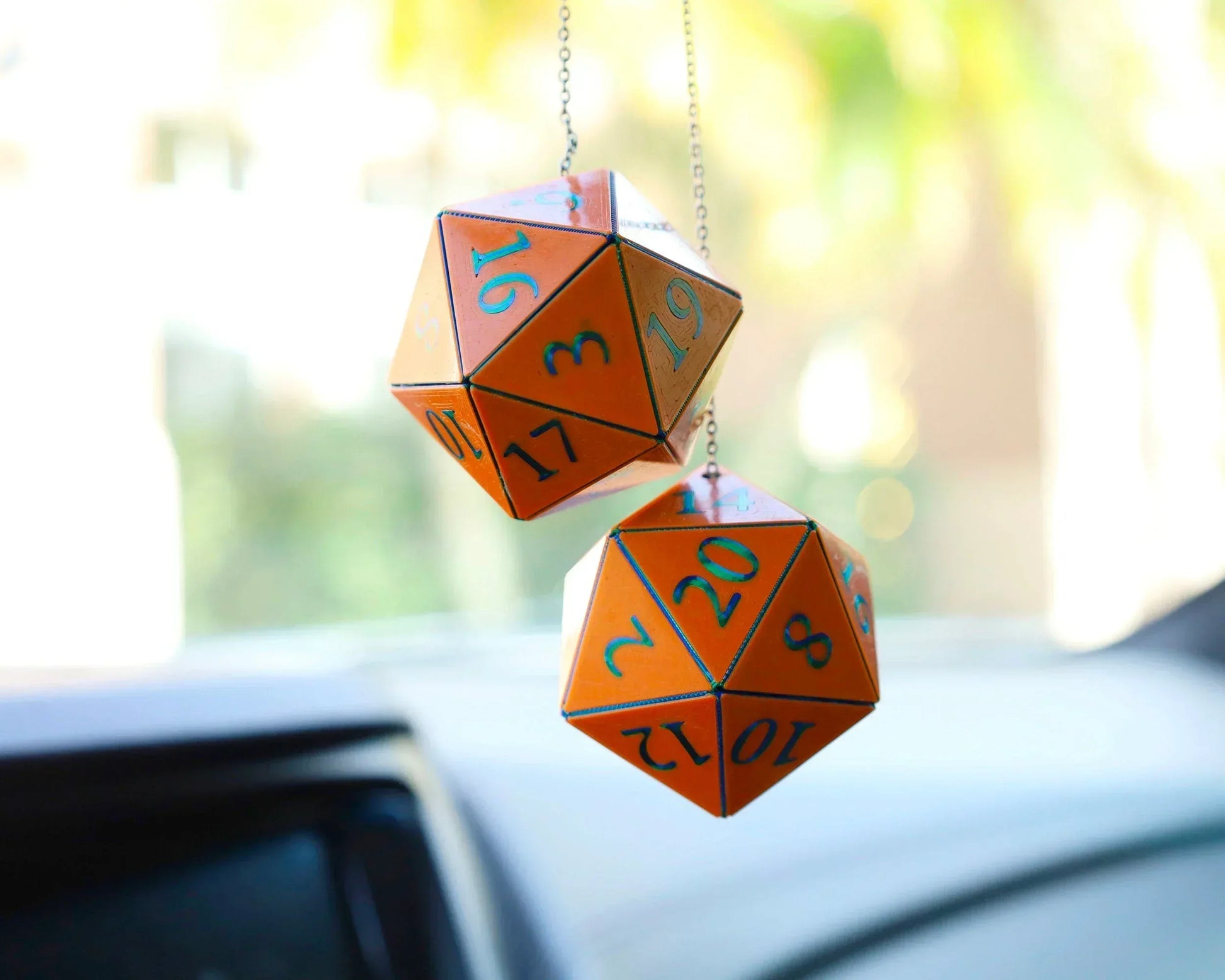 Orange twenty-sided dice car charm for tabletop RPG fans hanging in a vehicle.