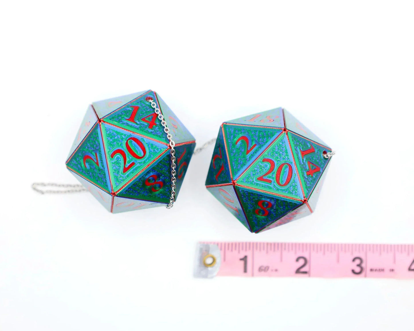 Pair of holographic 20-sided dice car charms with chain, shown next to a measuring tape