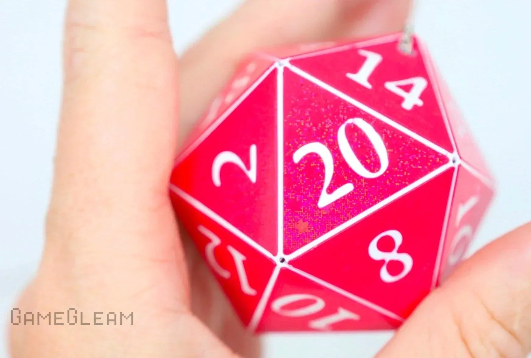 Hand holding a pink holographic 20-sided dice charm with white numbers