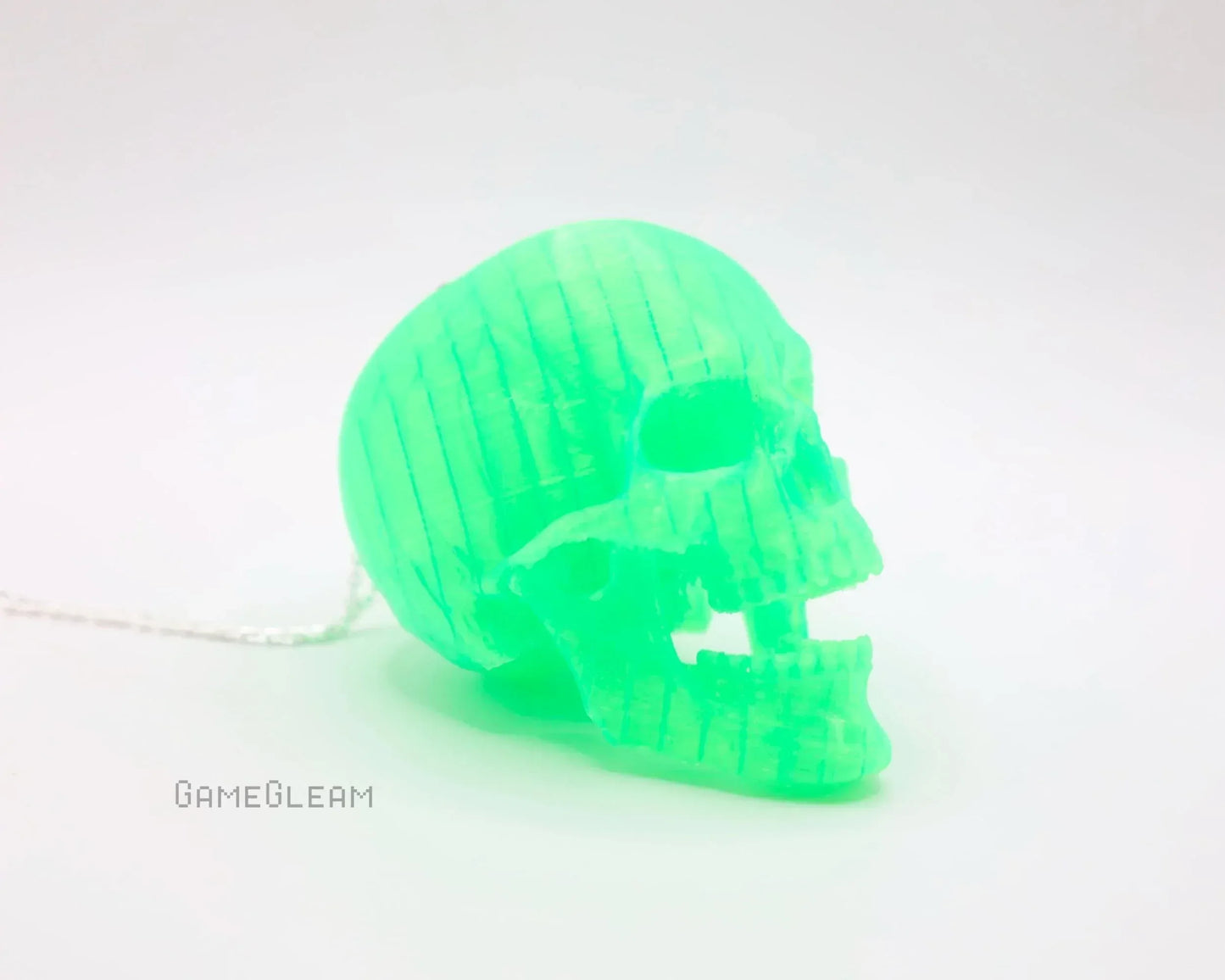 Glowing green acrylic skull charm with chain on white background, gamer gift accessory