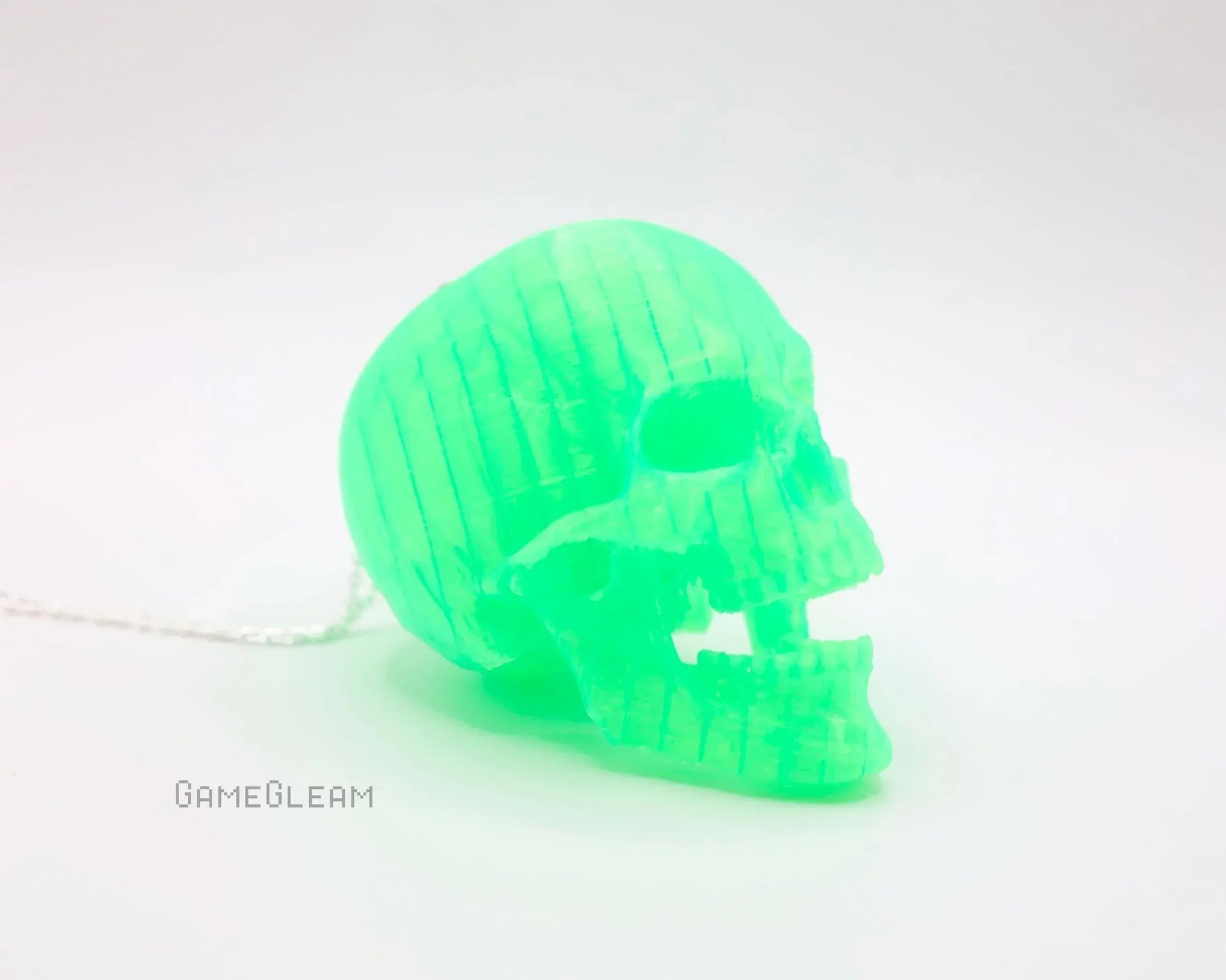 Glowing green acrylic skull charm with chain on white background, gamer gift accessory