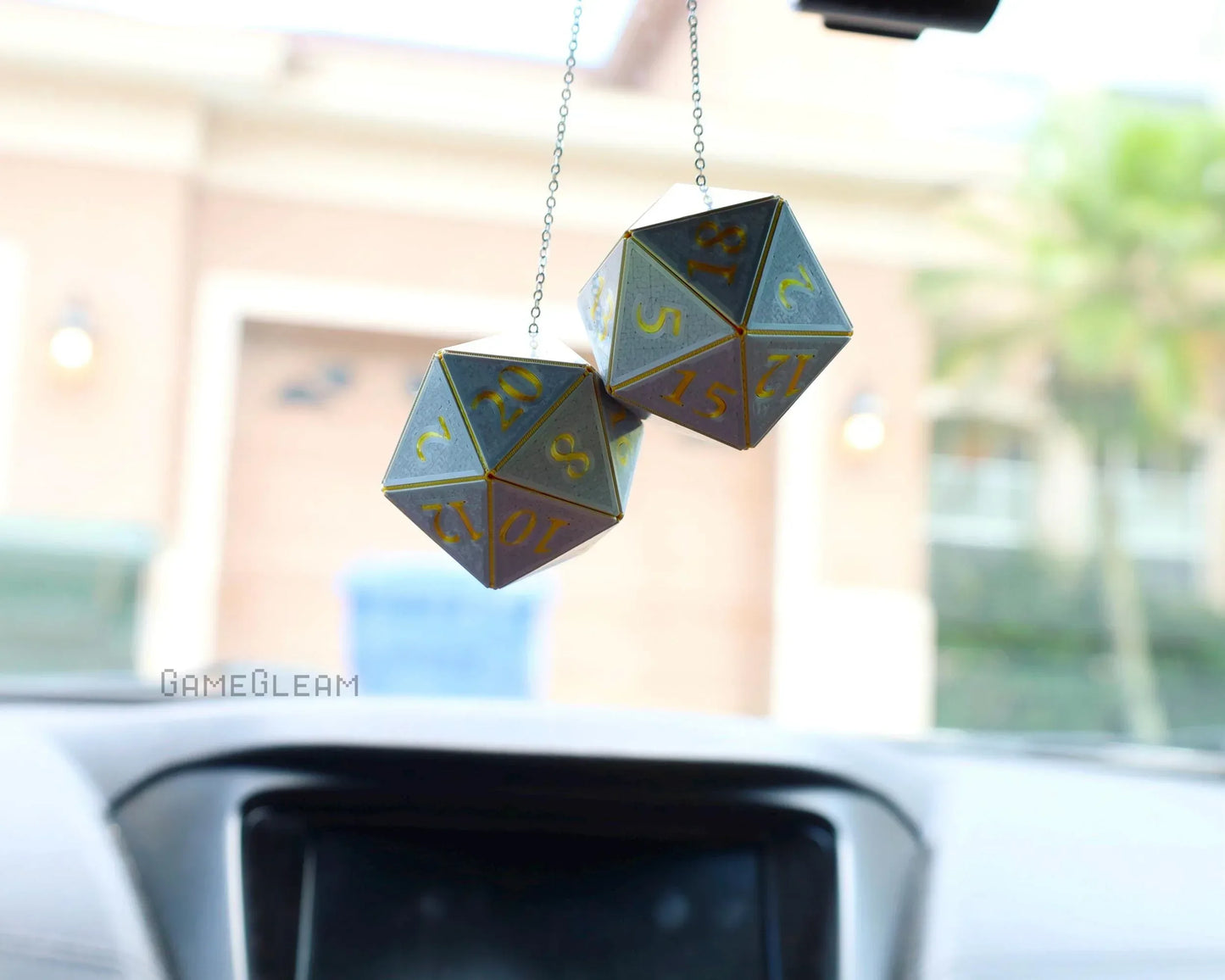 Gray and gold twenty-sided dice car charm hanging from rearview mirror
