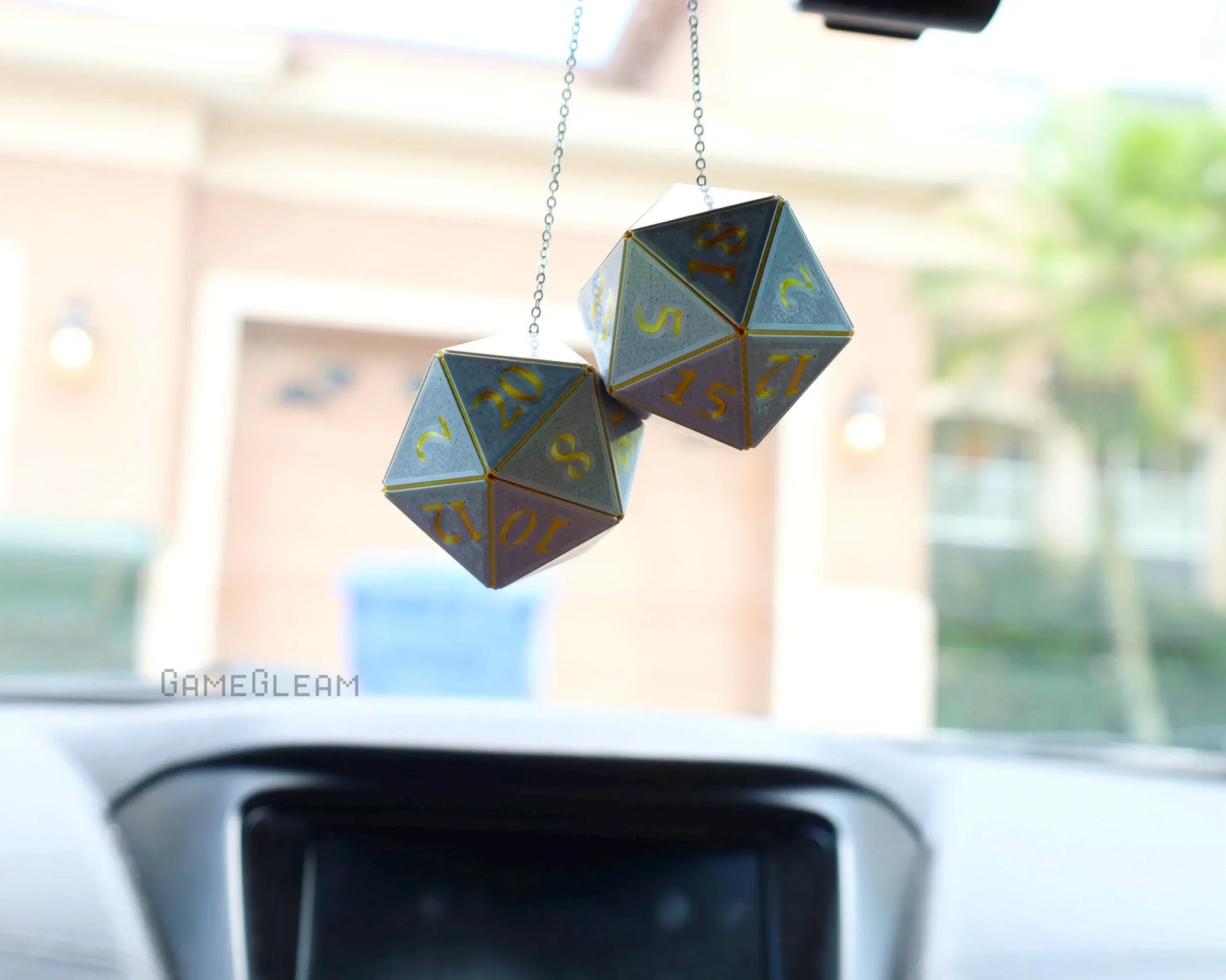 Gray and gold twenty-sided dice car charm hanging from rearview mirror