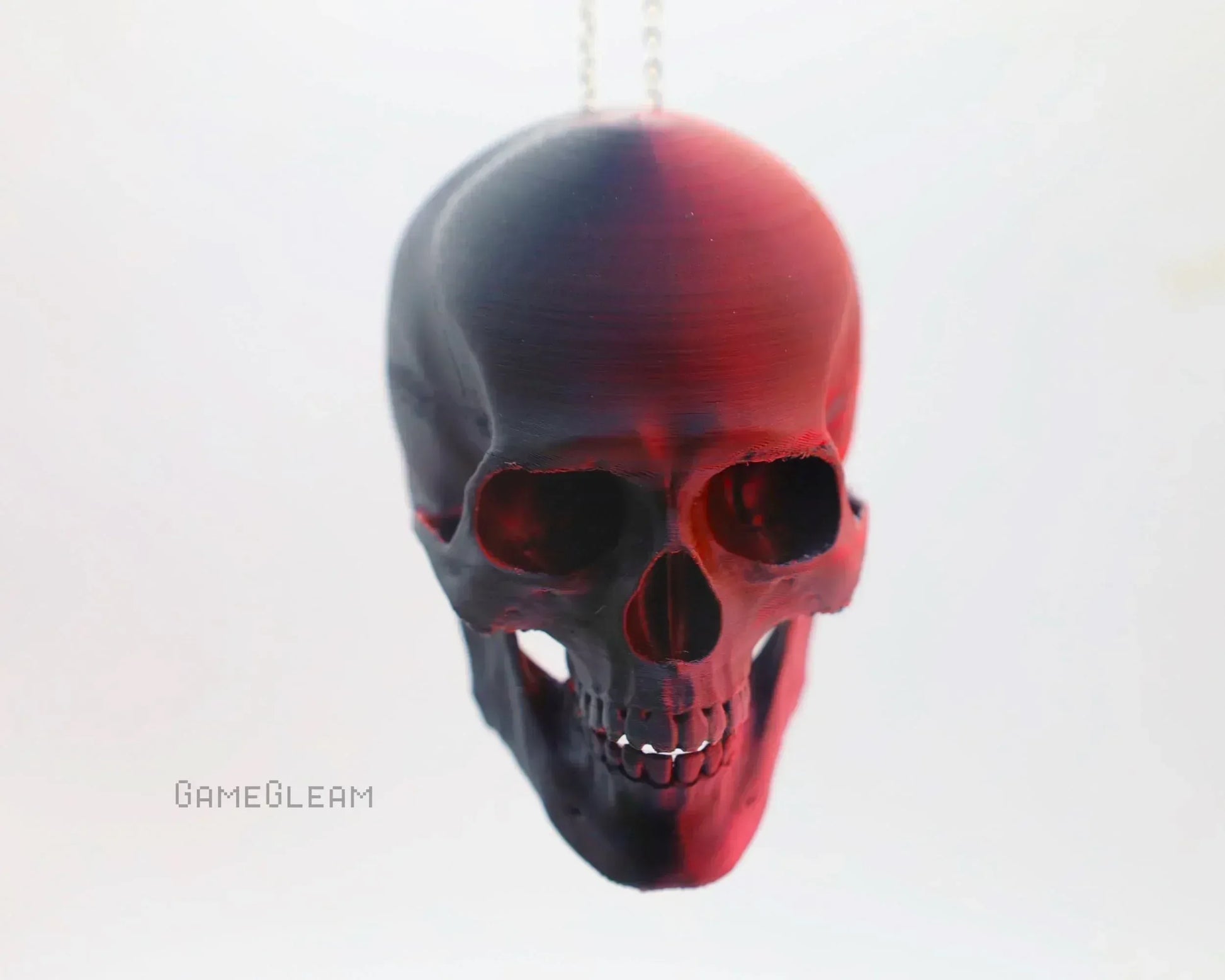Black and red skull-shaped car accessory with chain on white background, gamer gift decor.