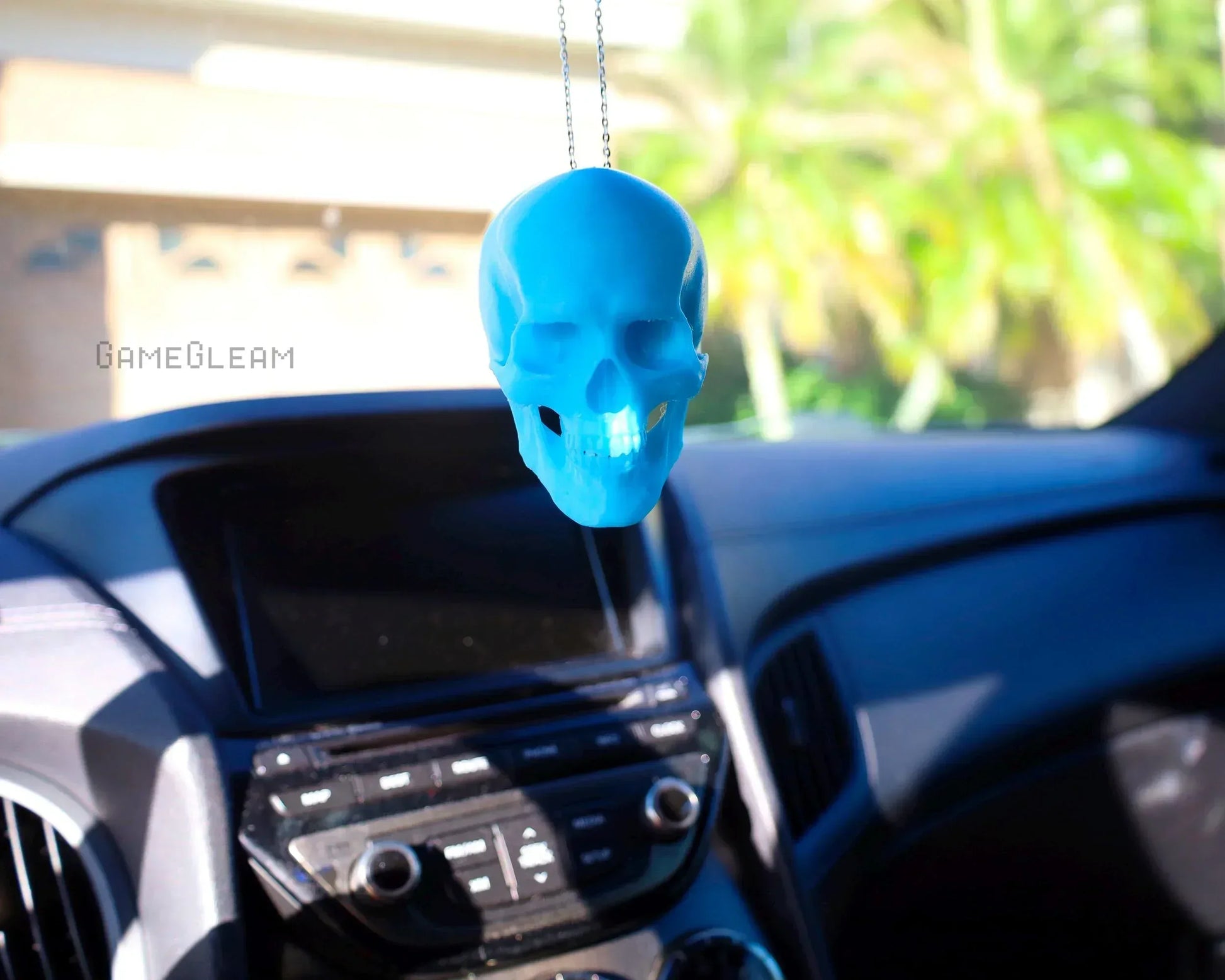 Blue skull car charm hanging from rearview mirror in modern car interior