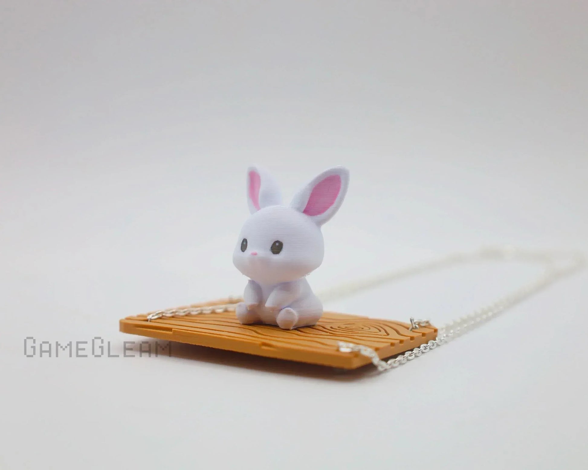 Cute handmade white bunny figure with pink ears sitting on a wooden swing pendant necklace