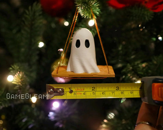 Handmade ghost ornament on swing with measuring tape, holiday tree in background
