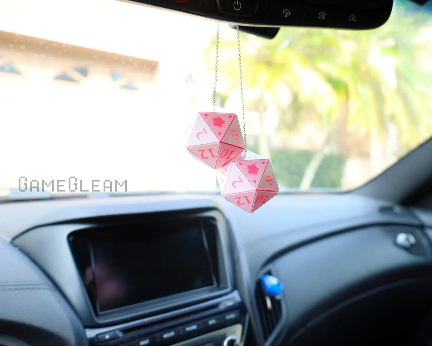 Pink twenty-sided dice hanging as car mirror charm in modern vehicle interior