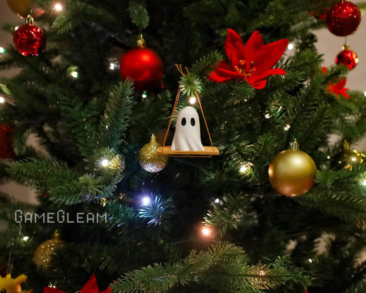 Handmade ghost ornament on Christmas tree with red, gold baubles and holiday lights