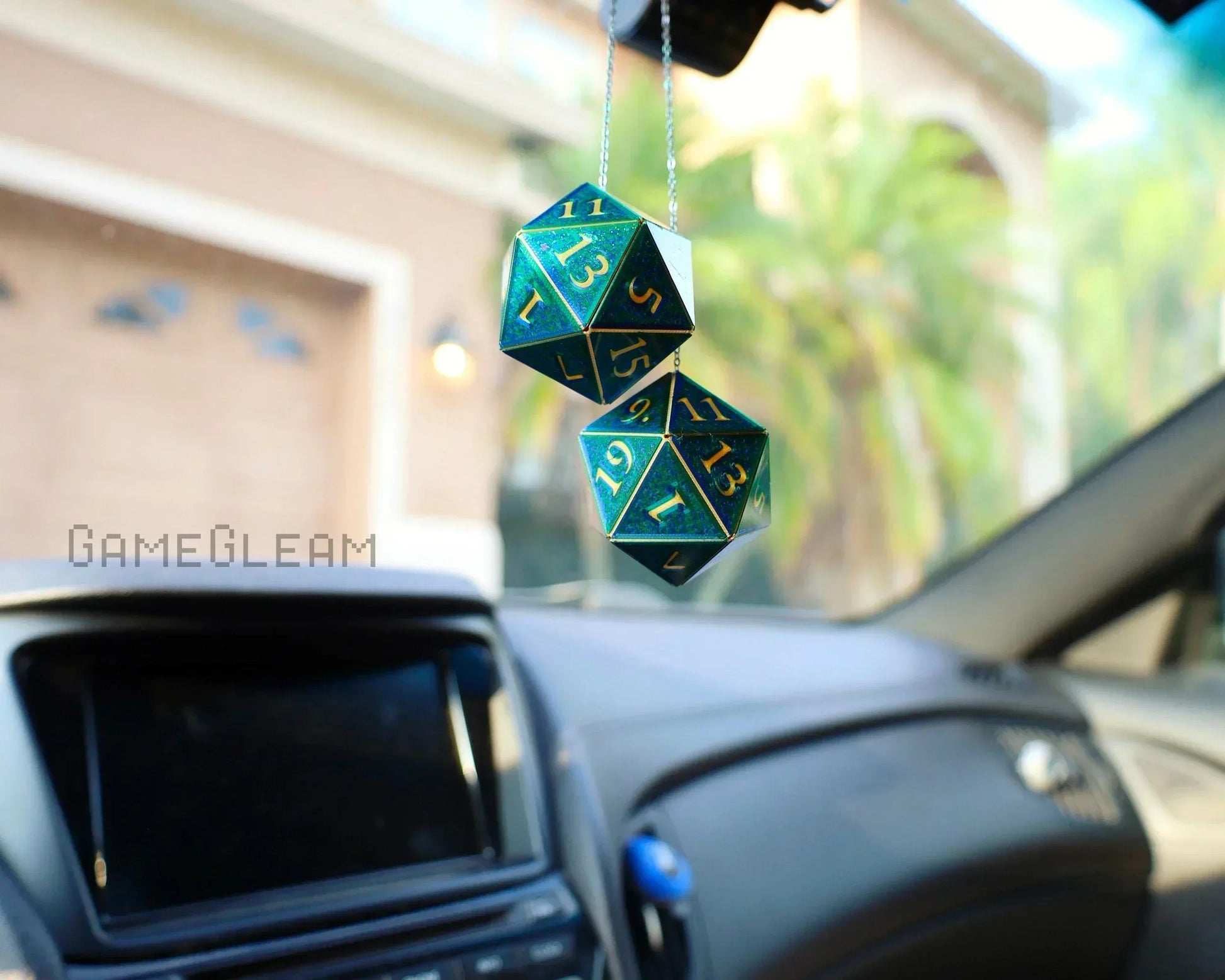 Holographic green and gold twenty-sided dice car charm hanging from rearview mirror