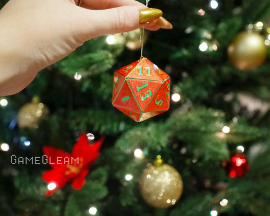 Hand holding a red 20-sided dice ornament with green numbers on a Christmas tree.