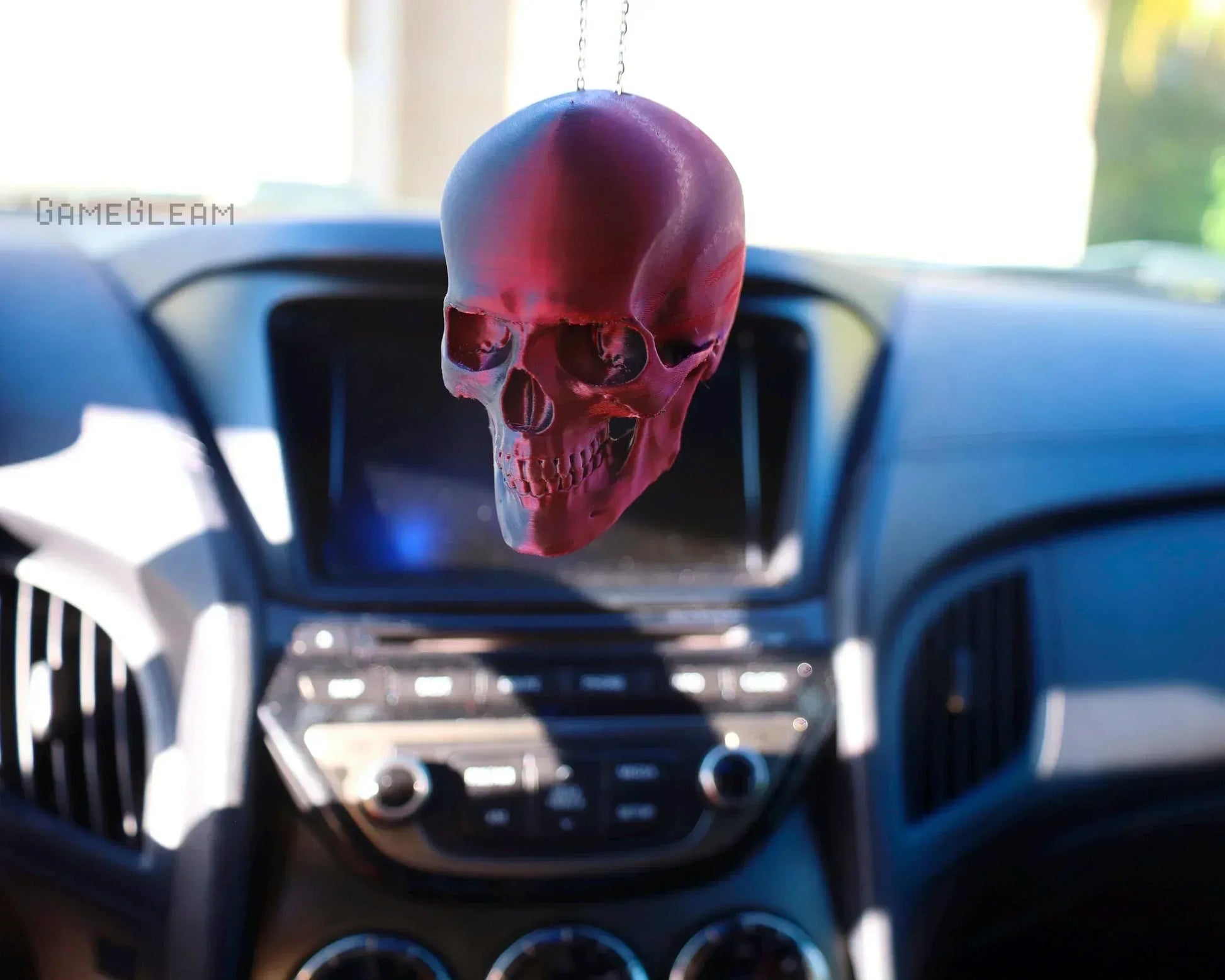 Handmade red skull car charm hanging from rearview mirror in a modern car interior