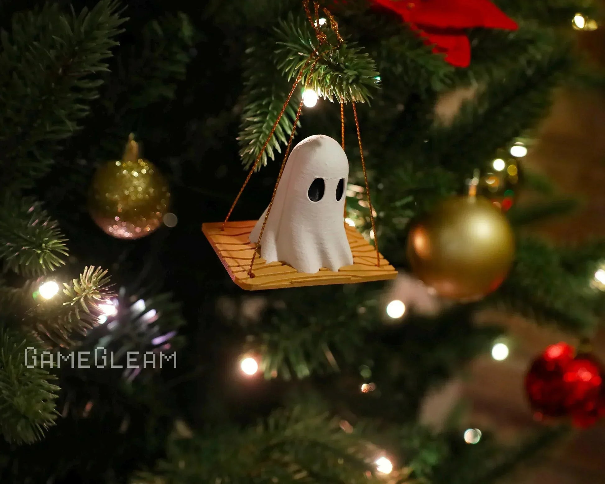 Handmade ghost ornament on a wooden swing hanging from a decorated Christmas tree