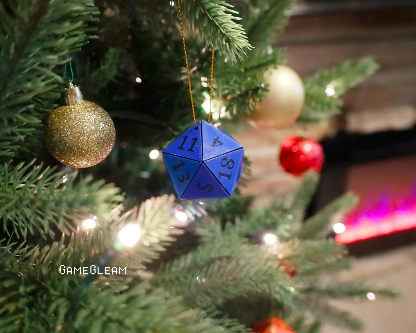 Blue 20-sided dice ornament hanging on a decorated Christmas tree with baubles and lights