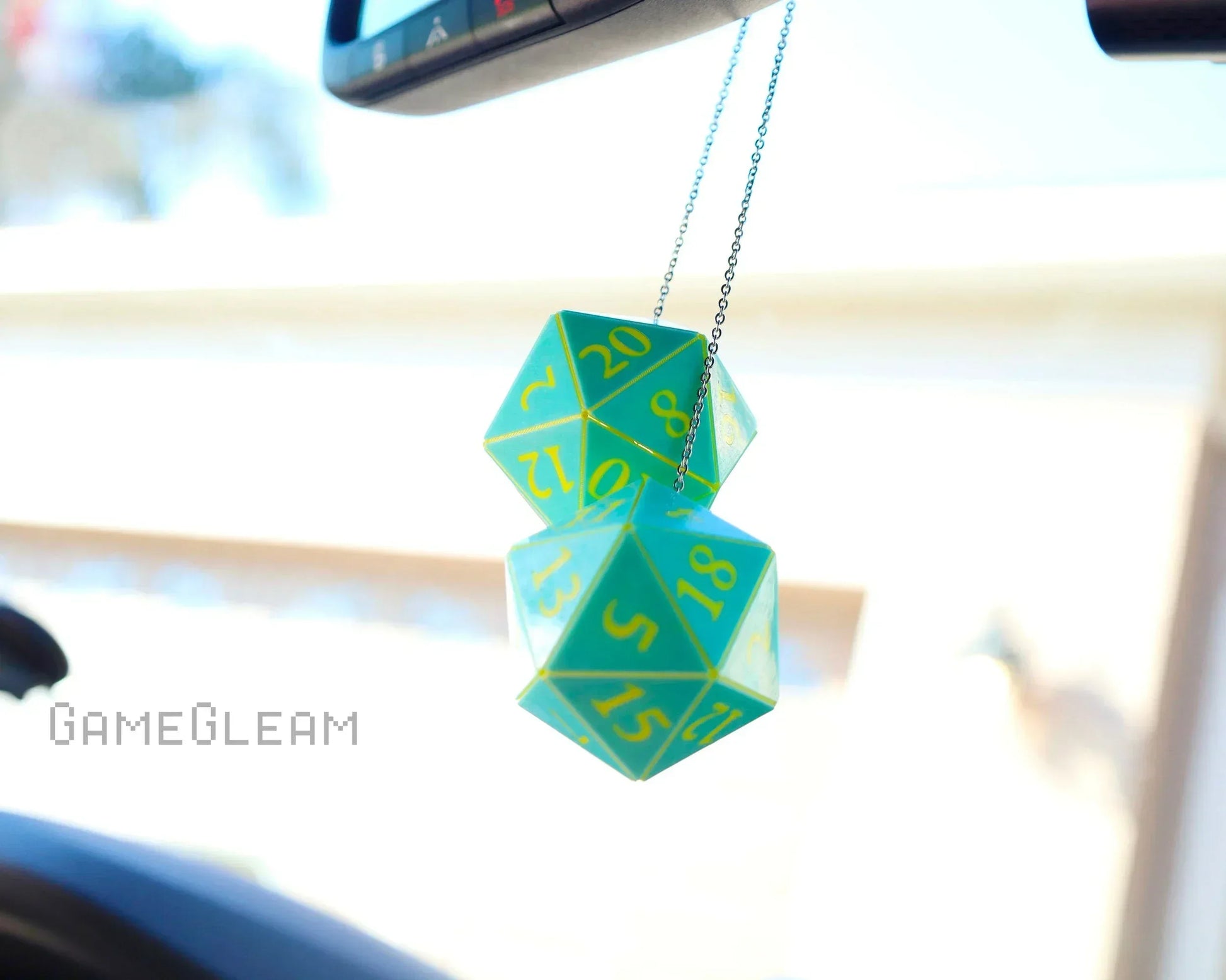 Green and yellow twenty-sided dice car charm hanging from rearview mirror