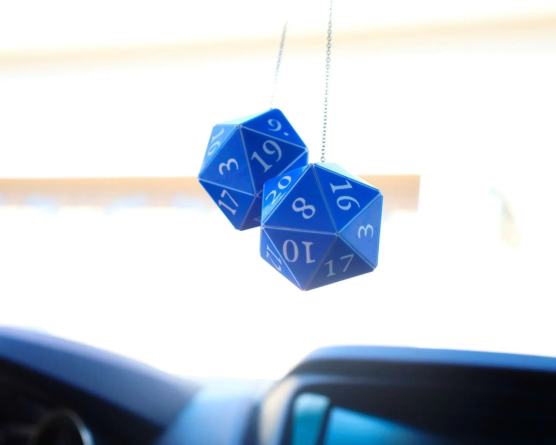 Blue twenty-sided dice hanging as car charms inside a vehicle