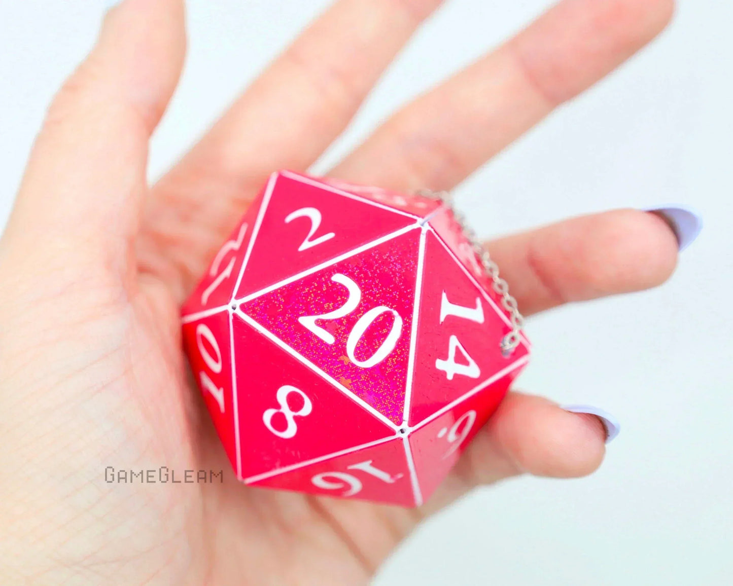 Hand holding a large pink holographic twenty-sided dice car charm with silver chain