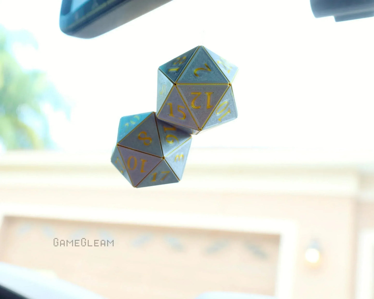 Holographic twenty-sided dice car charm with gold numbers hanging from rearview mirror