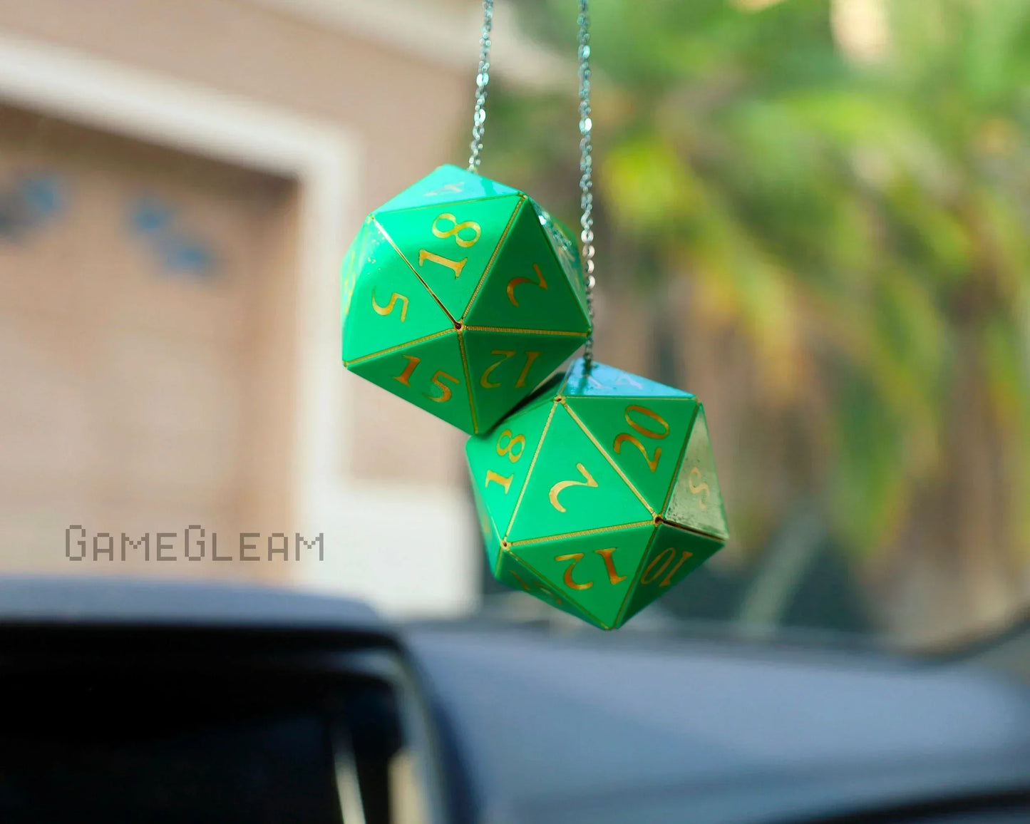 Green twenty-sided dice car charm with gold numbers hanging from rearview mirror