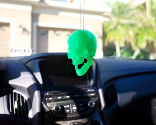 Neon green resin skull car charm hanging from rearview mirror in a modern car interior